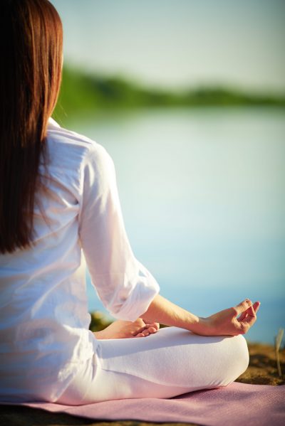 Half back of meditating woman relaxing in pose of lotus outdoors